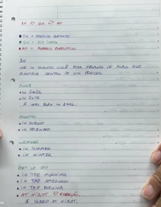 Anotação de aula sobre as preposições in, on e at, com regra curta e exemplos
