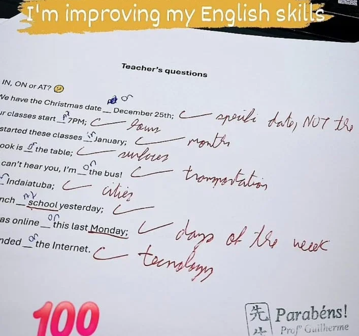Atividade de in, on e at corrigida pelo professor Guilherme, com nota 100 e carimbo de parabéns