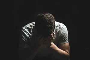 Homem com as mãos no rosto, frustrado por estudar inglês há anos e não evoluir