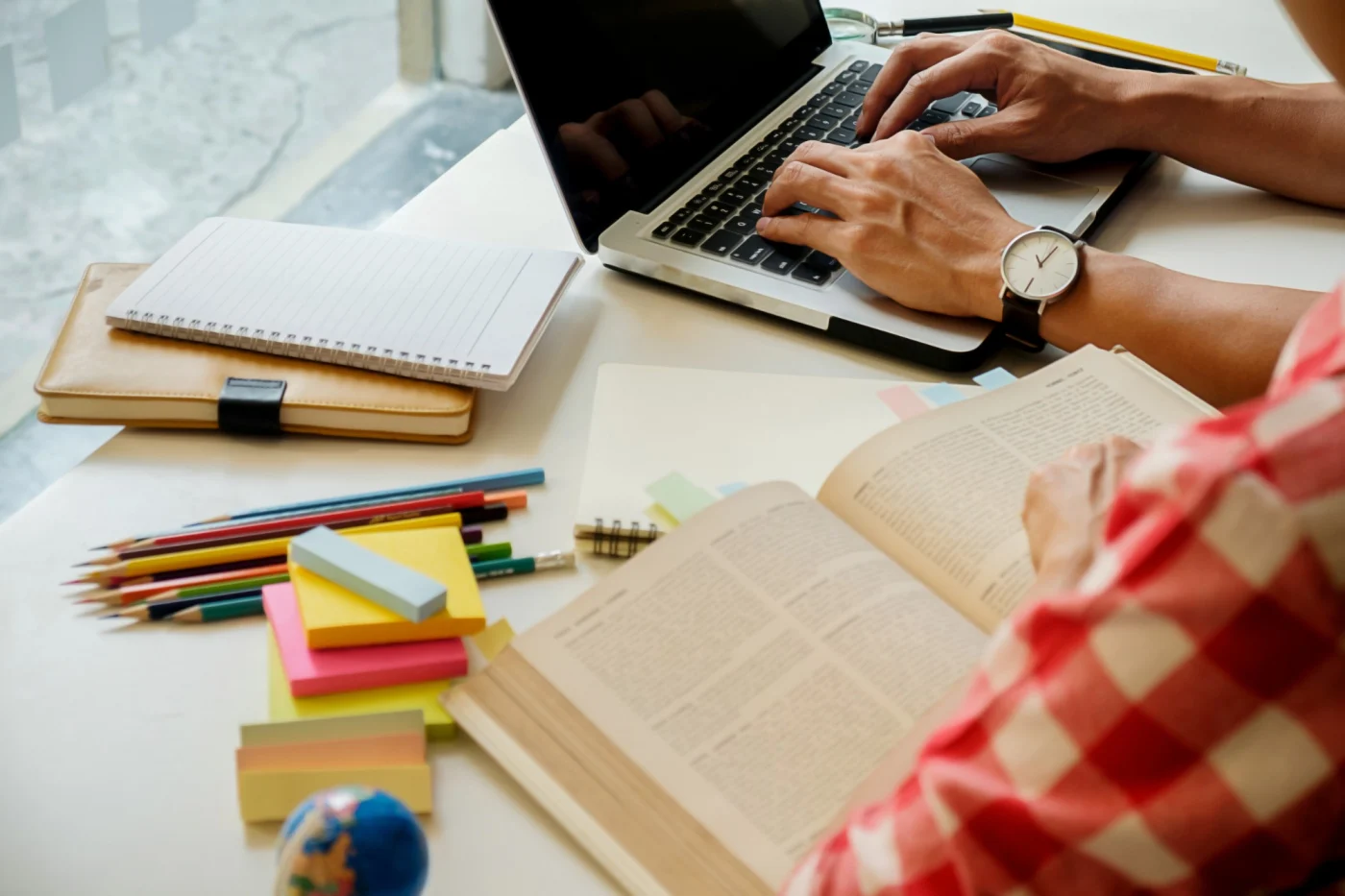 Profissional estudando inglês de negócios com notebook, livro e anotações