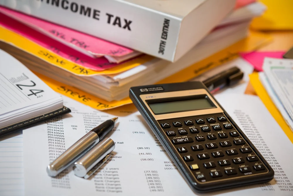 Calculadora, caneta e relatórios financeiros sobre a mesa, rotina de quem estuda inglês para finanças