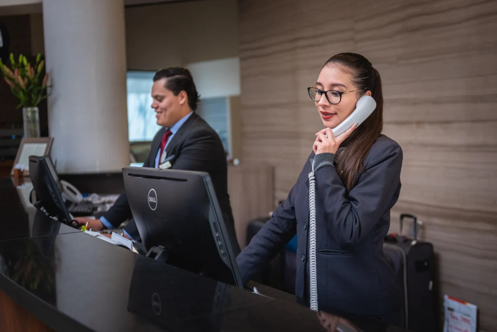Recepcionistas atendendo na recepção de um hotel, profissionais que desenvolvem inglês para hotelaria