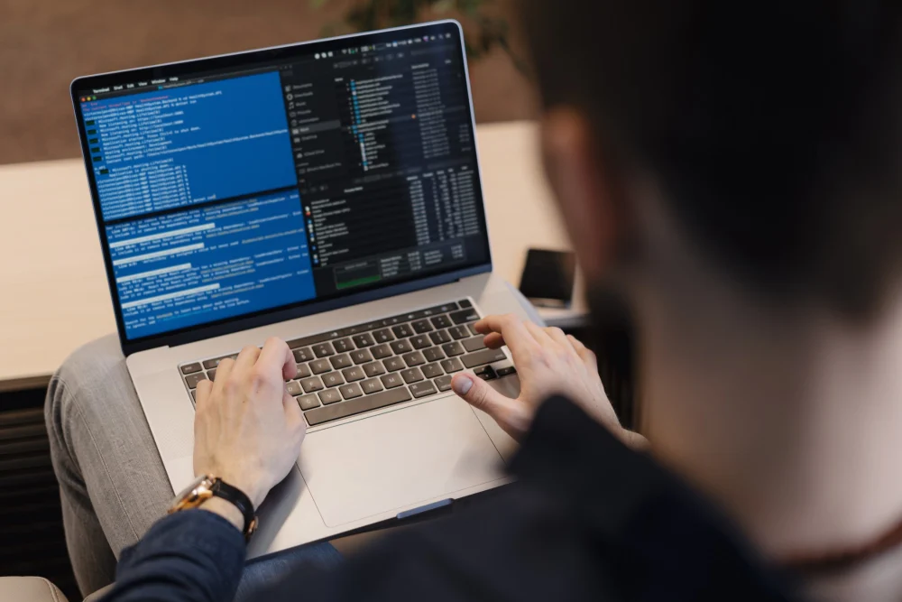 Programador escrevendo código no notebook, profissional de TI que desenvolve inglês para tecnologia